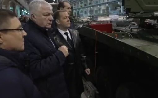 Медведев в кожаном пальто гуляет между танками